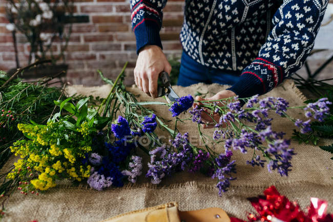 Colheita floristas mãos cortando flores em saquear à mesa — Fotografia de Stock
