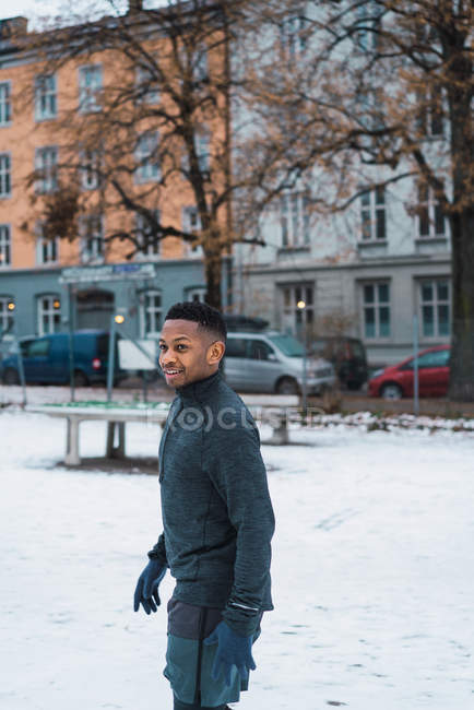 Alegre hombre negro calentándose en el patio de la ciudad - foto de stock