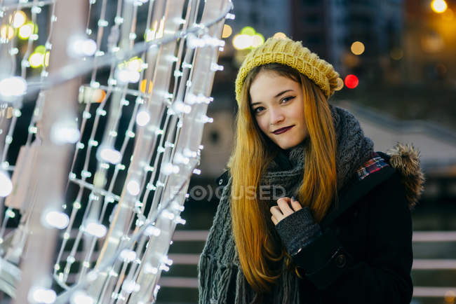 Mulher sorridente posando na iluminação festiva e olhando para a câmera — Fotografia de Stock