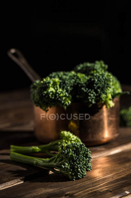 Close up view of fresh bimi broccolis in copper sauce pot on wooden table — Stock Photo