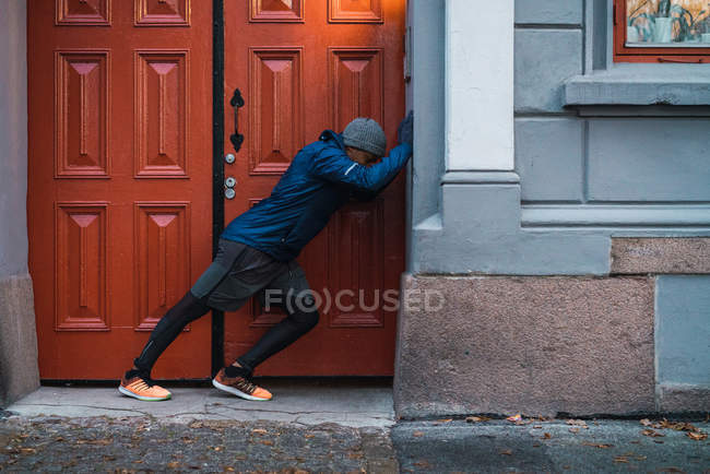 Vista lateral del hombre negro calentándose en la ciudad - foto de stock
