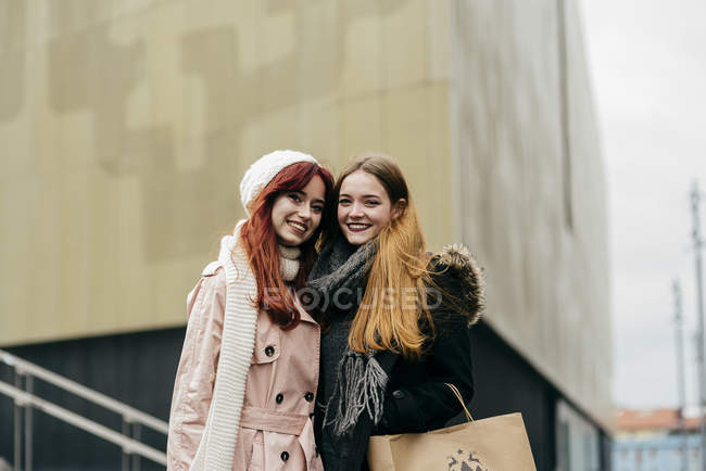 Hübsche Frauen, die sich auf der Straße umarmen und in die Kamera schauen — Stockfoto