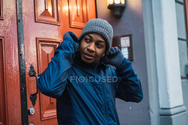 Retrato de homem em pé na porta enquanto coloca o chapéu e olhando para longe — Fotografia de Stock