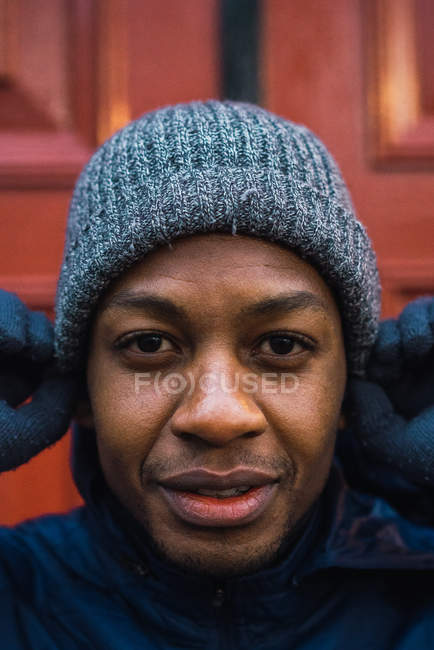 Retrato del hombre poniéndose el sombrero y mirando a la cámara - foto de stock
