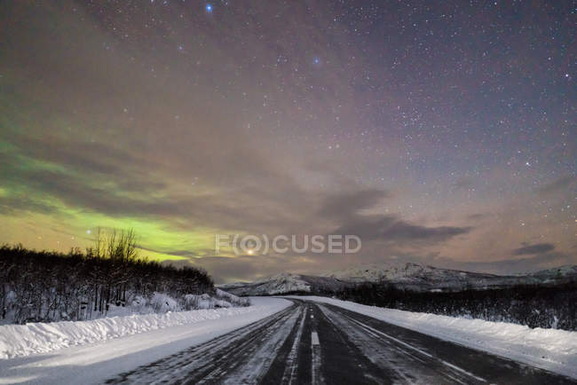 Perspective view to asphalt road and nature covered with snow in winter night. — Stock Photo