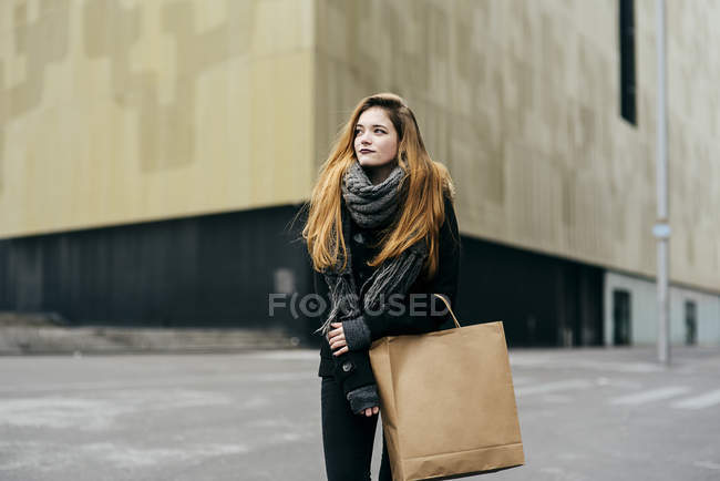 Porträt einer jungen Frau mit Papierhandtasche, die auf der Straße posiert — Stockfoto