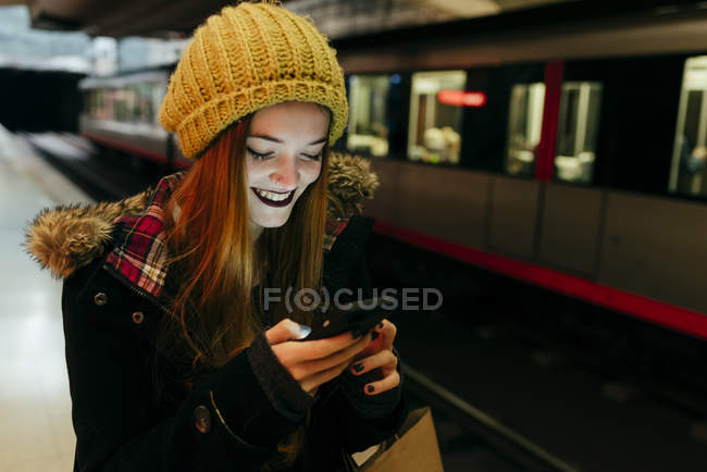 Femme souriante bavarder sur smartphone dans le métro — Photo de stock