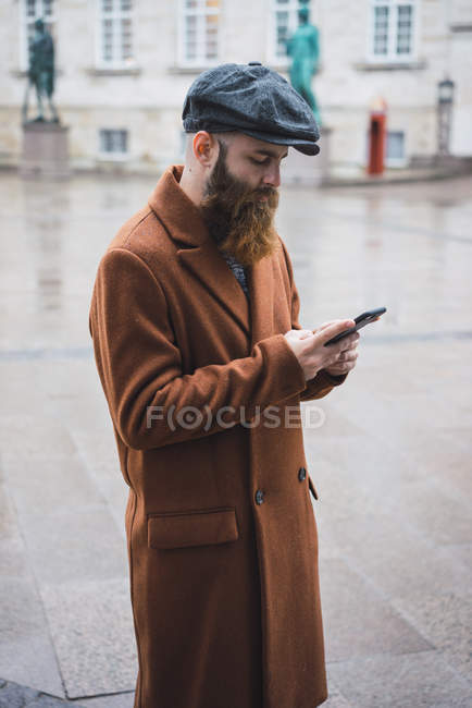 Side view of bearded man using phone on street scene — Stock Photo