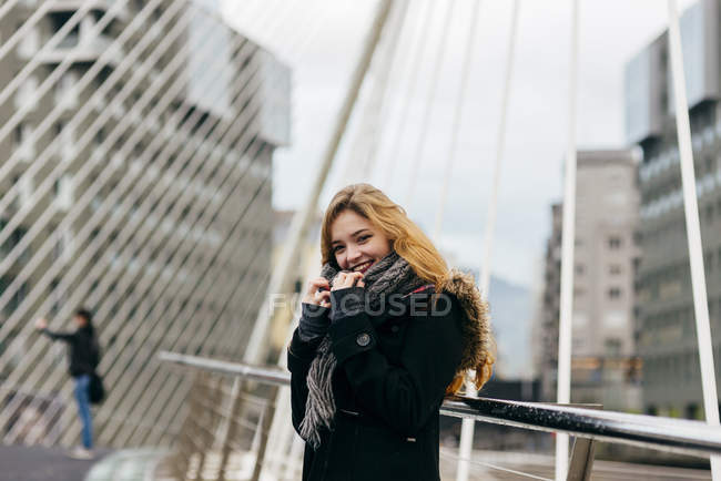 Porträt einer stilvollen blonden Frau, die auf einer Brücke posiert und in die Kamera blickt — Stockfoto