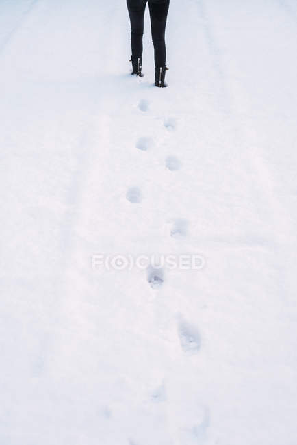 Задній вид обтинання людину, що йде на білому снігу взимку. — стокове фото