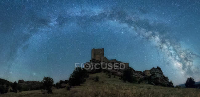 Vista panorámica al castillo construido en la colina bajo el cielo estrellado claro de la noche
. - foto de stock