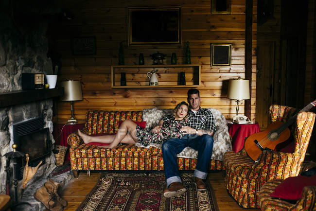 Abbracciare uomo e donna sdraiati sul divano a casa . — Foto stock
