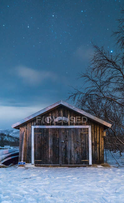 Exterior de la pequeña casa de madera bajo el cielo estrellado por la noche . - foto de stock