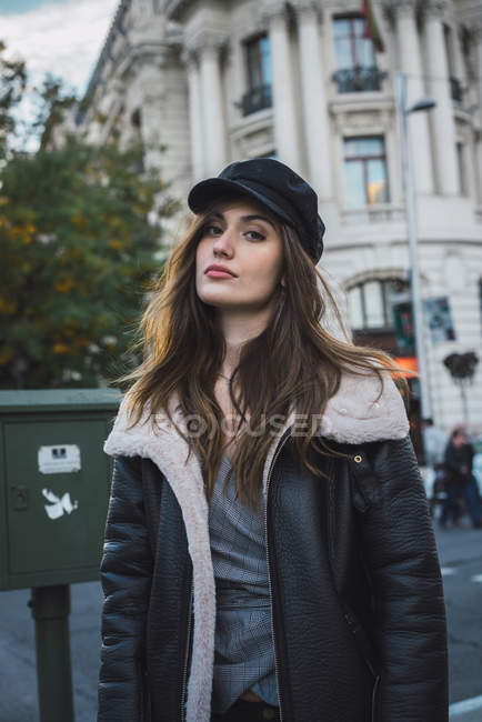 Donna in elegante berretto a piedi sulla strada e guardare la fotocamera — Foto stock