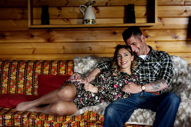 Sorridente abbracciando coppia rilassante sul divano a casa . — Foto stock
