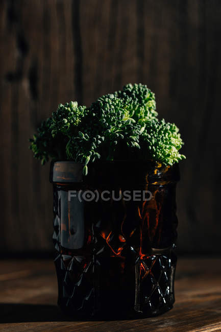 Close up vista de fresco bimi brócolis cacho em jarro vermelho na mesa de madeira . — Fotografia de Stock