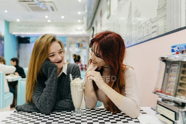 Portrait of cheerful women having cocktail and looking at each one — Stock Photo