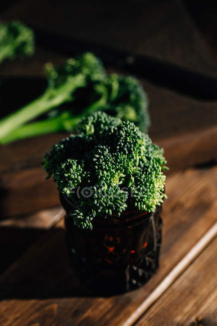 Close up view of fresh bimi broccoli in glass on rustic wooden table — Stock Photo