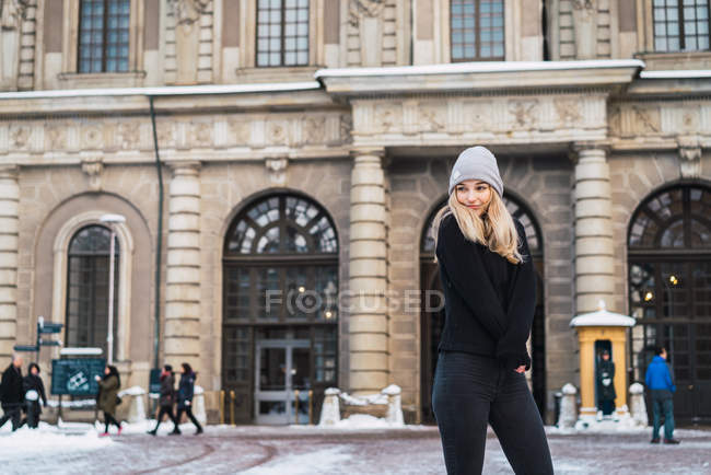 Front view of young blonde woman posing in winter town — Stock Photo