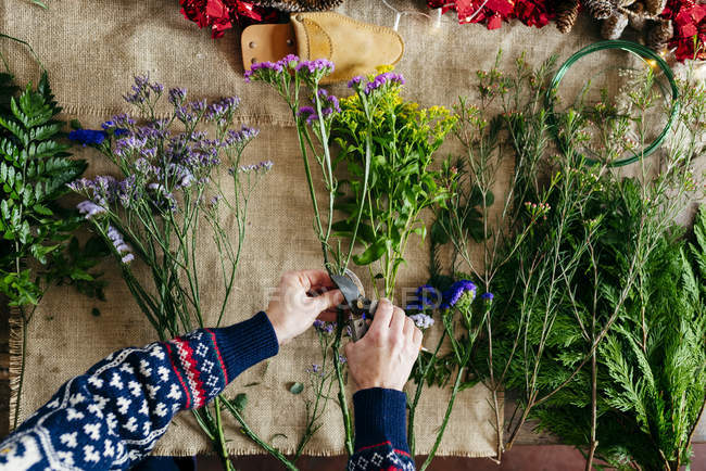 Schnitthände schneiden Blumen für Blumenstrauß über Leinenstoff. — Stockfoto