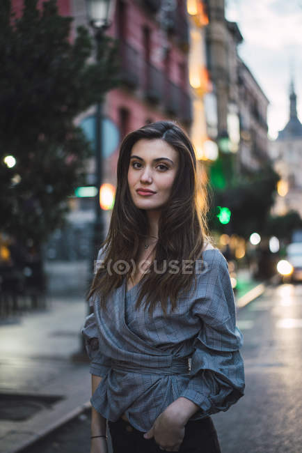 Junge brünette Frau steht auf der Straße der Stadt und schaut in die Kamera. — Stockfoto