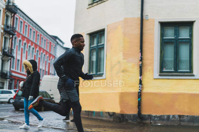 Vista lateral del hombre deportivo corriendo en escena callejera - foto de stock