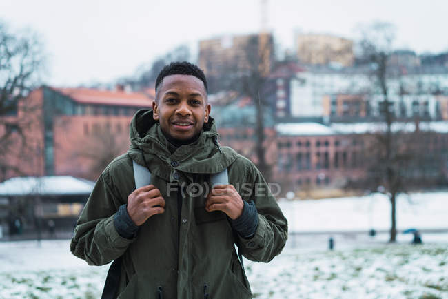 Retrato del alegre turista en ropa de abrigo mirando a la cámara en la calle nevada . - foto de stock