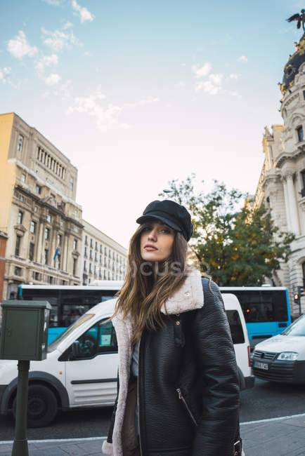Brünettes Mädchen in warmem Mantel und Mütze, das auf der Straße läuft und in die Kamera schaut — Stockfoto