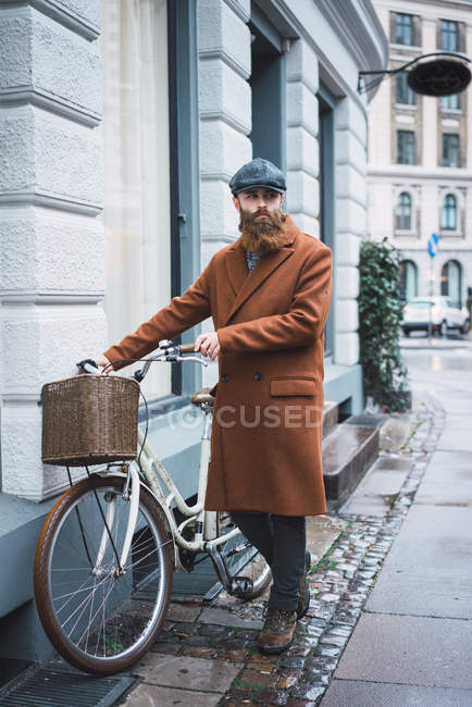 Ritratto di uomo barbuto con bicicletta vintage in strada — Foto stock