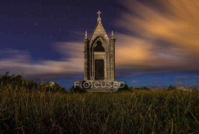 Exterior pequena igreja construída no campo verde ao anoitecer — Fotografia de Stock
