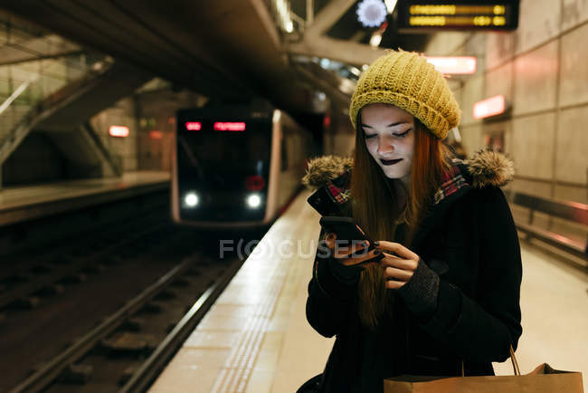 Retrato de mulher jovem usando smartphone na estação no metrô . — Fotografia de Stock