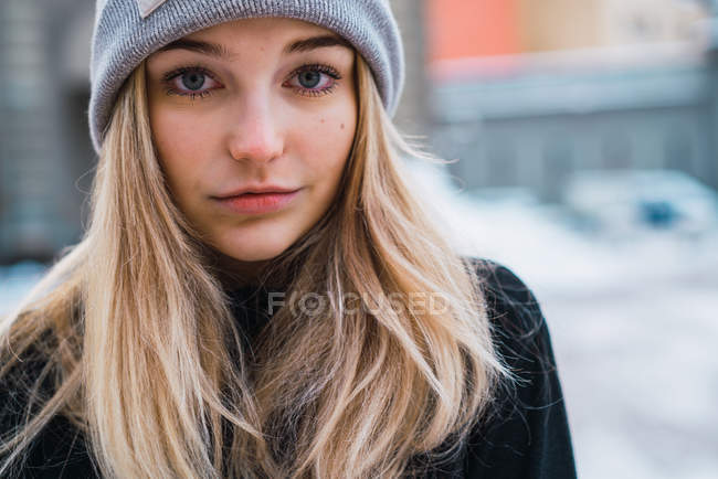 Close up portrait of young blonde woman posing at winter town and looking at camera — Stock Photo