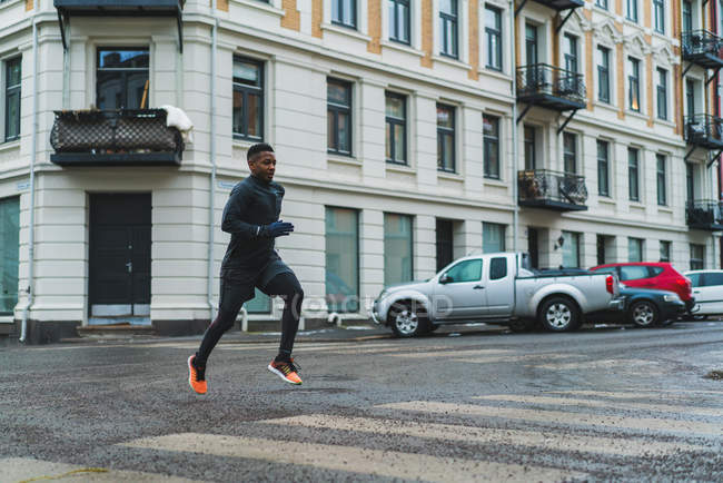 Vue latérale du joggeur sportif qui court dans la rue — Photo de stock