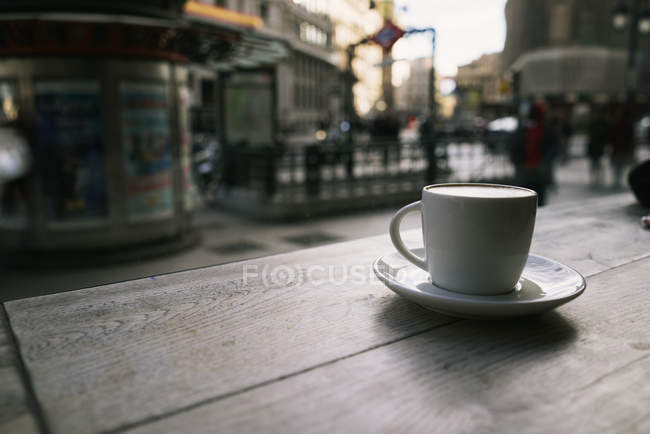 Close up view of fresh coffee placed on wooden table in urban cafe. — Stock Photo
