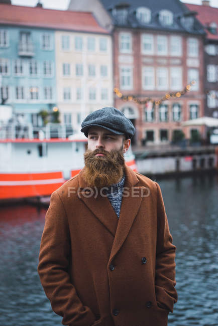 Портрет вдумчивого человека, позирующего у реки в городе — стоковое фото