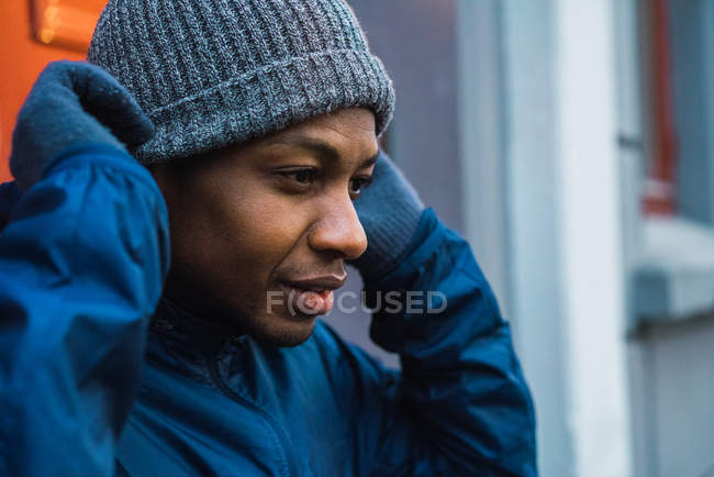 Portrait of thoughtful man putting on hat and looking ahead — Stock Photo