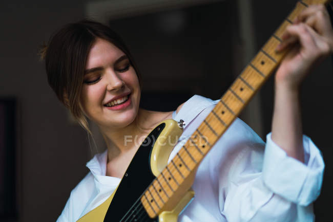 Портрет улыбающейся женщины, играющей на гитаре — стоковое фото