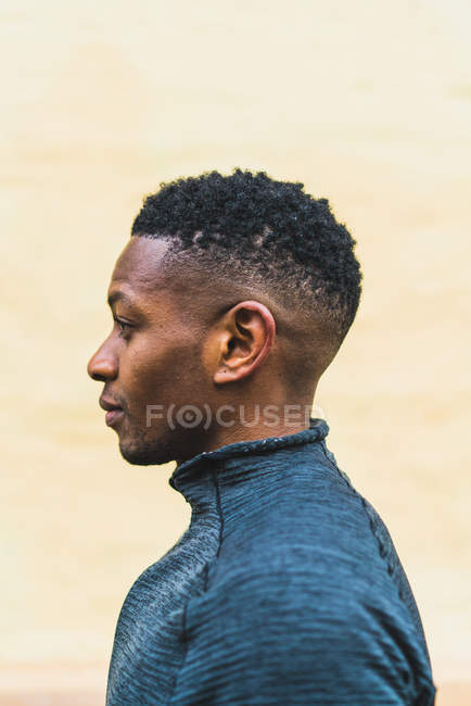 Side view of fit man in warm sportswear standing on street and looking away. — Stock Photo