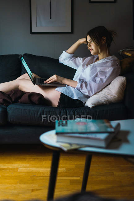 Vista laterale della donna seduta con laptop sul divano — Foto stock
