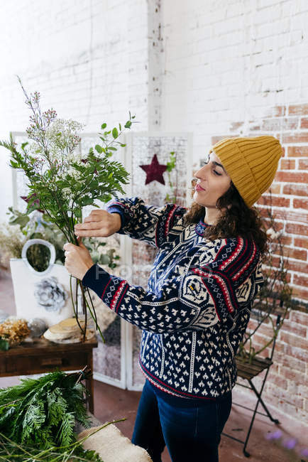 Seitenansicht einer Frau im Strickpullover, die Blumen arrangiert — Stockfoto