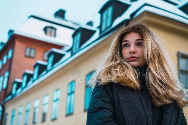 Vue grand angle de la femme blonde regardant loin sur la rue d'hiver — Photo de stock