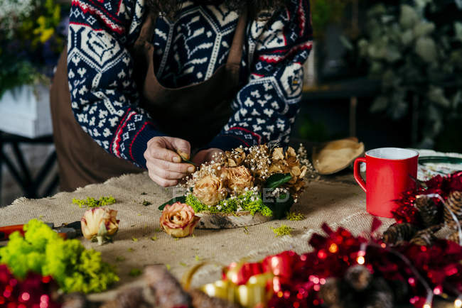 Cortar fêmea em avental fazendo composição floral em tecido de saque — Fotografia de Stock