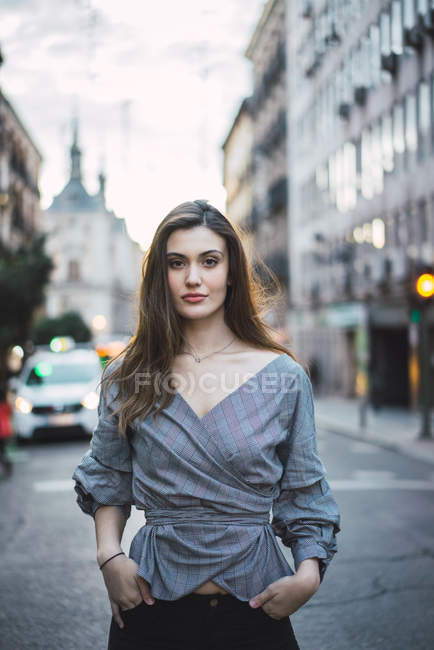 Jeune femme brune posant dans la rue urbaine et regardant la caméra — Photo de stock