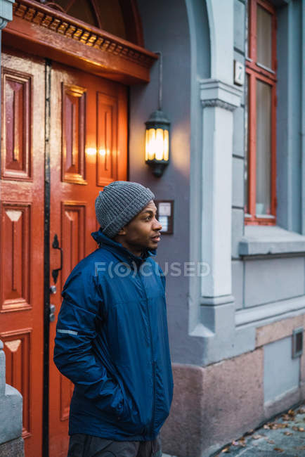 Vista lateral do homem em roupas casuais posando ao lado da porta na rua — Fotografia de Stock