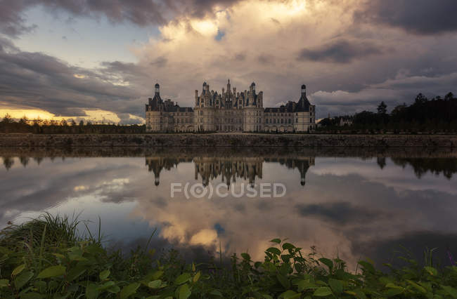 Vue lointaine du grand château et du lac sous un ciel nuageux — Photo de stock