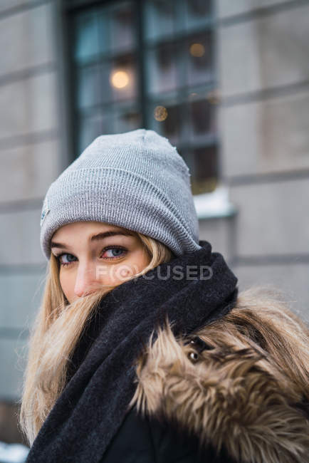 Bastante joven sensual mujer de pie en la calle nevada y mirando por encima del hombro a la cámara - foto de stock