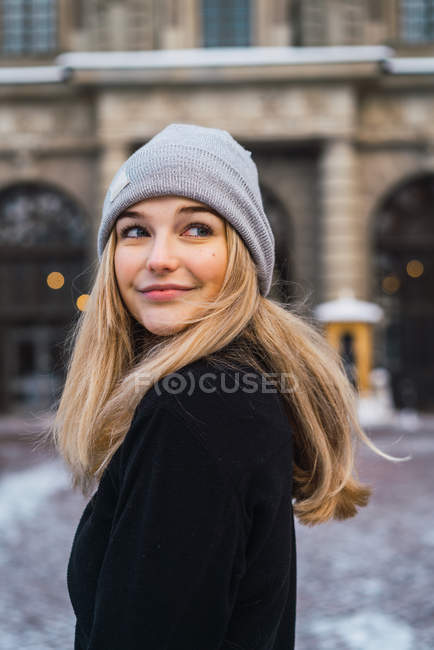 Retrato de mulher loira andando na cidade e olhando por cima do ombro — Fotografia de Stock