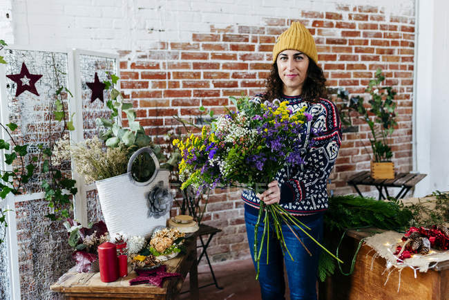 Портрет жінки в в'язаному светрі позує з гарним букетом — стокове фото