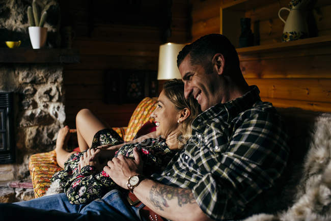 Seitenansicht des sich umarmenden Paares beim Entspannen auf dem Sofa im Chalet — Stockfoto