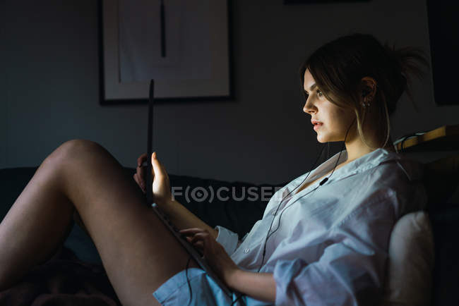 Side view of woman sitting with laptop on sofa and working — Stock Photo